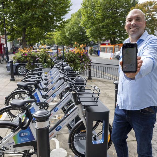 Man holding phone app up next to eBikes rack