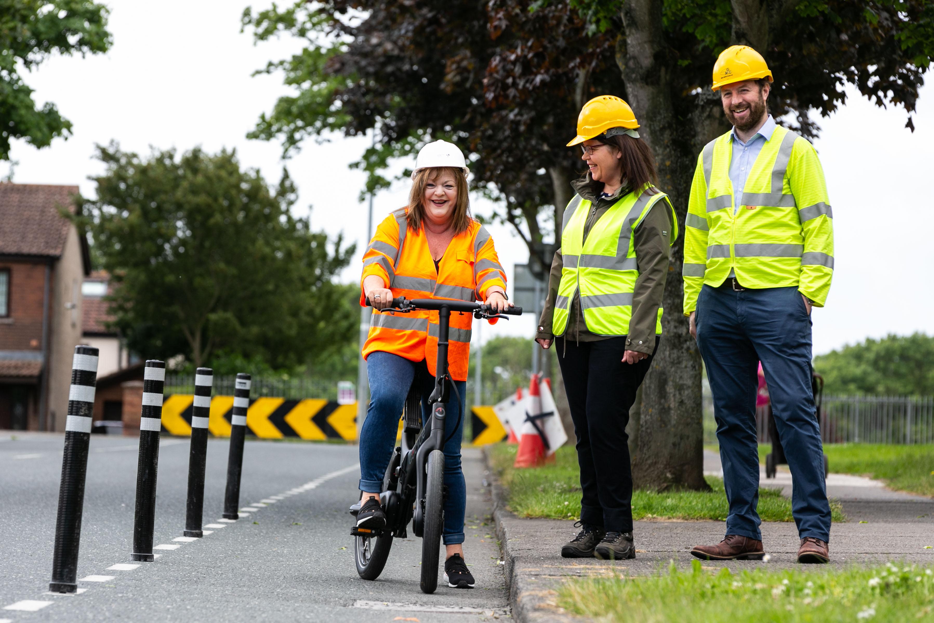 Woman in hard hat on bike with woman and man standing beside her
