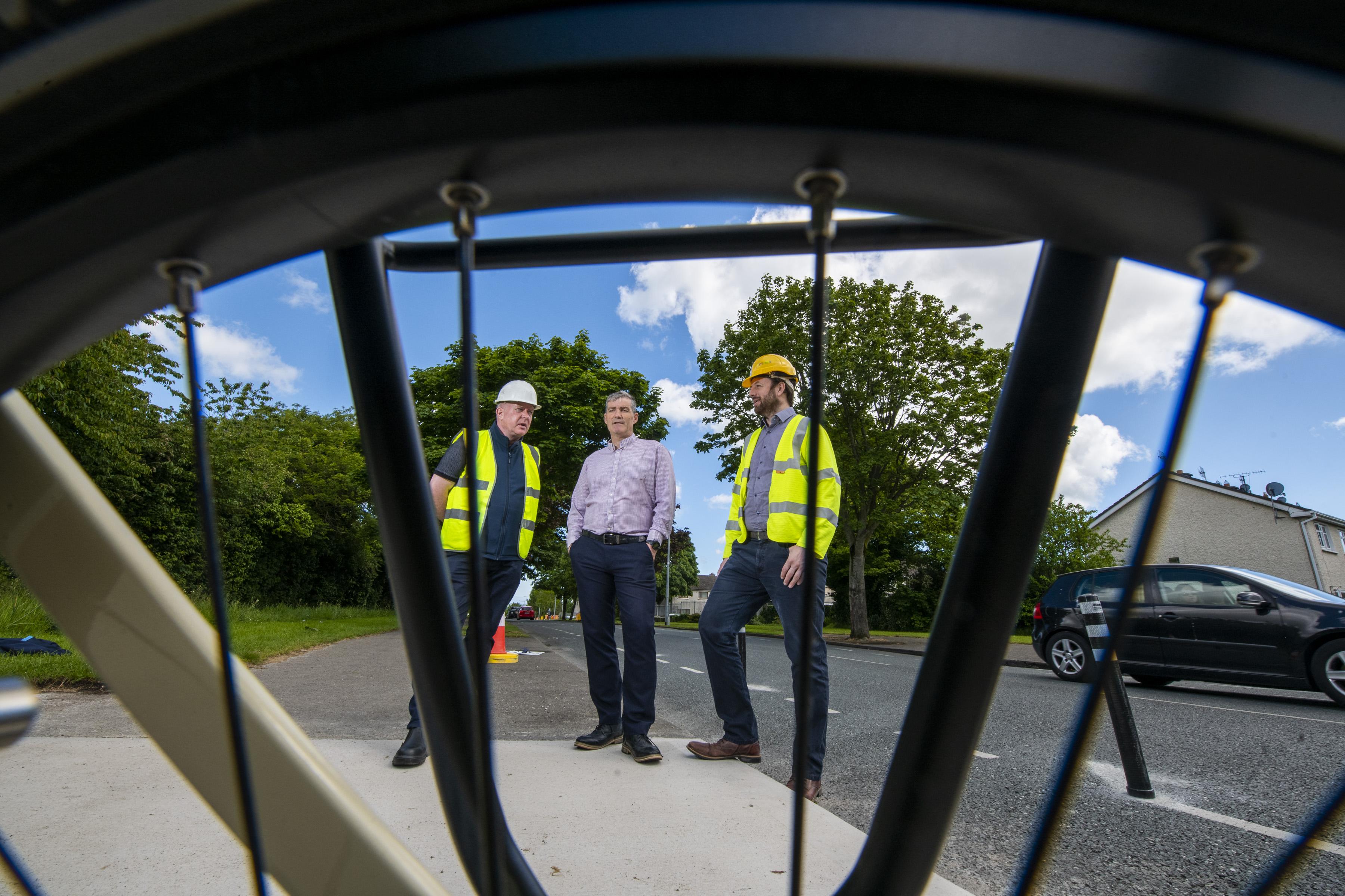 three men in construction PPE looking through bike spokes
