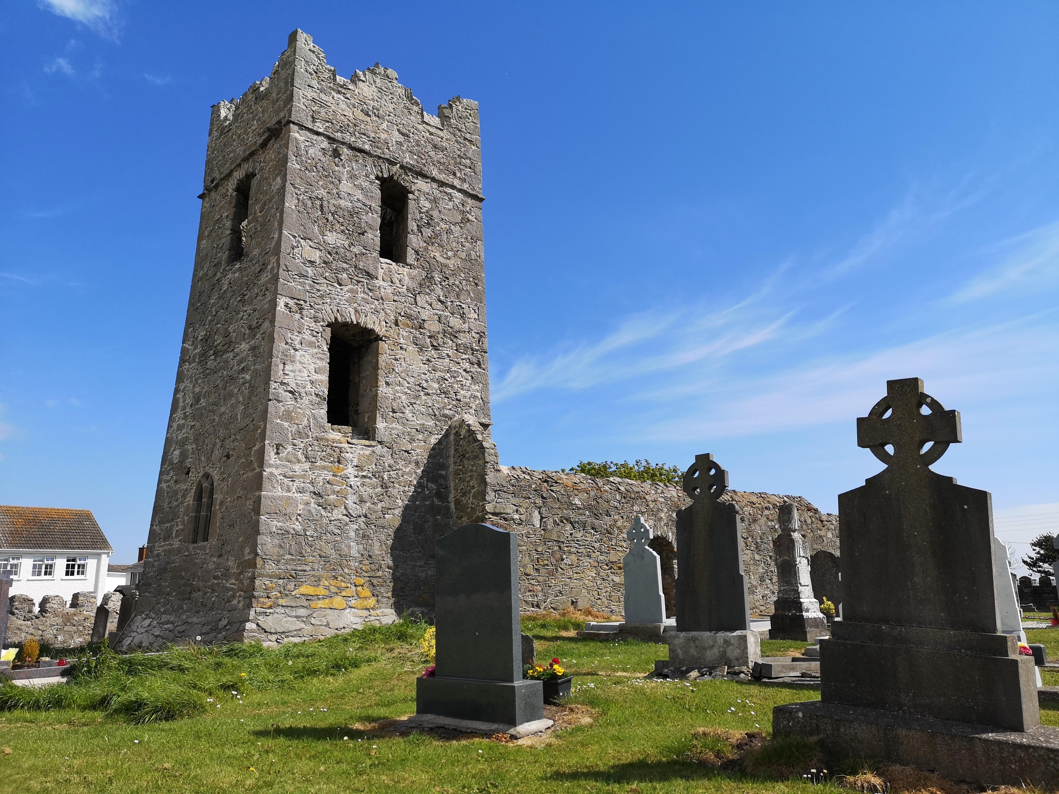 Ruin of church building with tower with graveyard