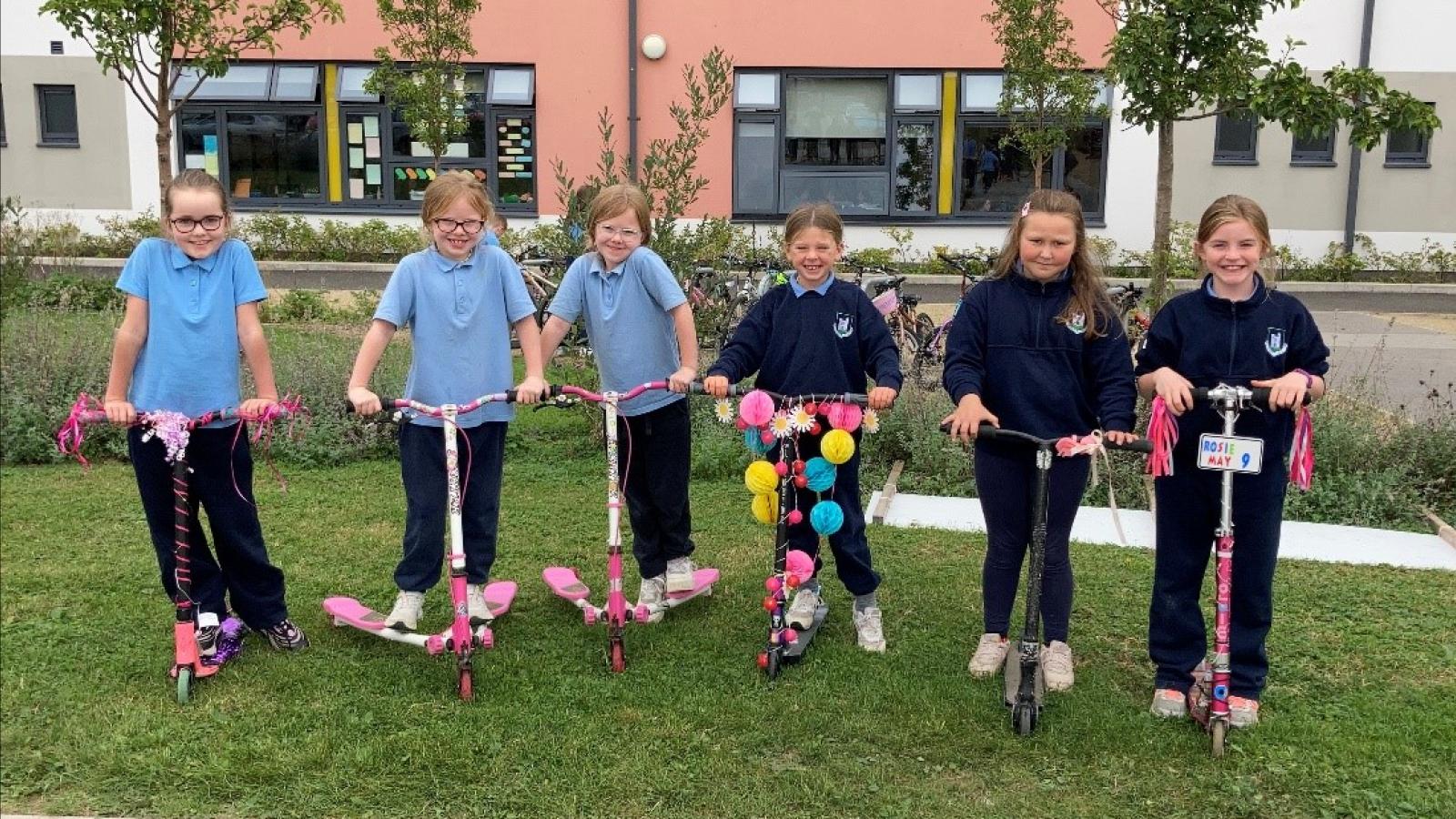 Line of children in uniform on scooters